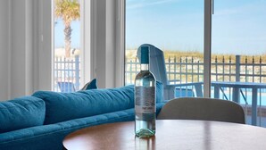 Een kamer met een blauwe bank, een ronde houten tafel en een fles wijn.