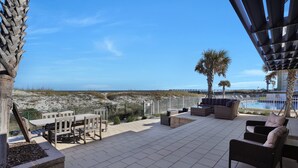 Een terras buiten met zitplaatsen, een zwembad en uitzicht op het strand.