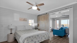 Een slaapkamer met een bed, een nachtkastje, een blauwe bank en een plafondventilator.