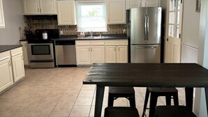 A kitchen with white cabinets, stainless steel appliances, a dark countertop, and a ceiling fan. - Newly renovated- 2.5 mi to Downtown Riverfront (Owensboro)