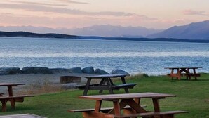 A lakeside view with picnic tables and mountains in the background. - Cottage Bliss Mountain Oasis (Rexford)