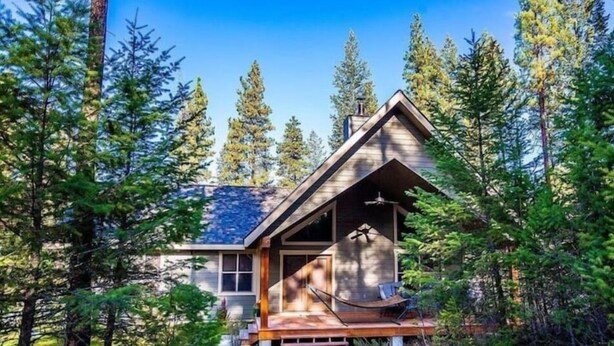 A cabin with a wooden deck, large windows, and a chimney. - Cottage Bliss Mountain Oasis (Rexford)