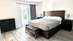 Une chambre à coucher comprenant un lit, un banc, un ventilateur de plafond et une table de chevet.