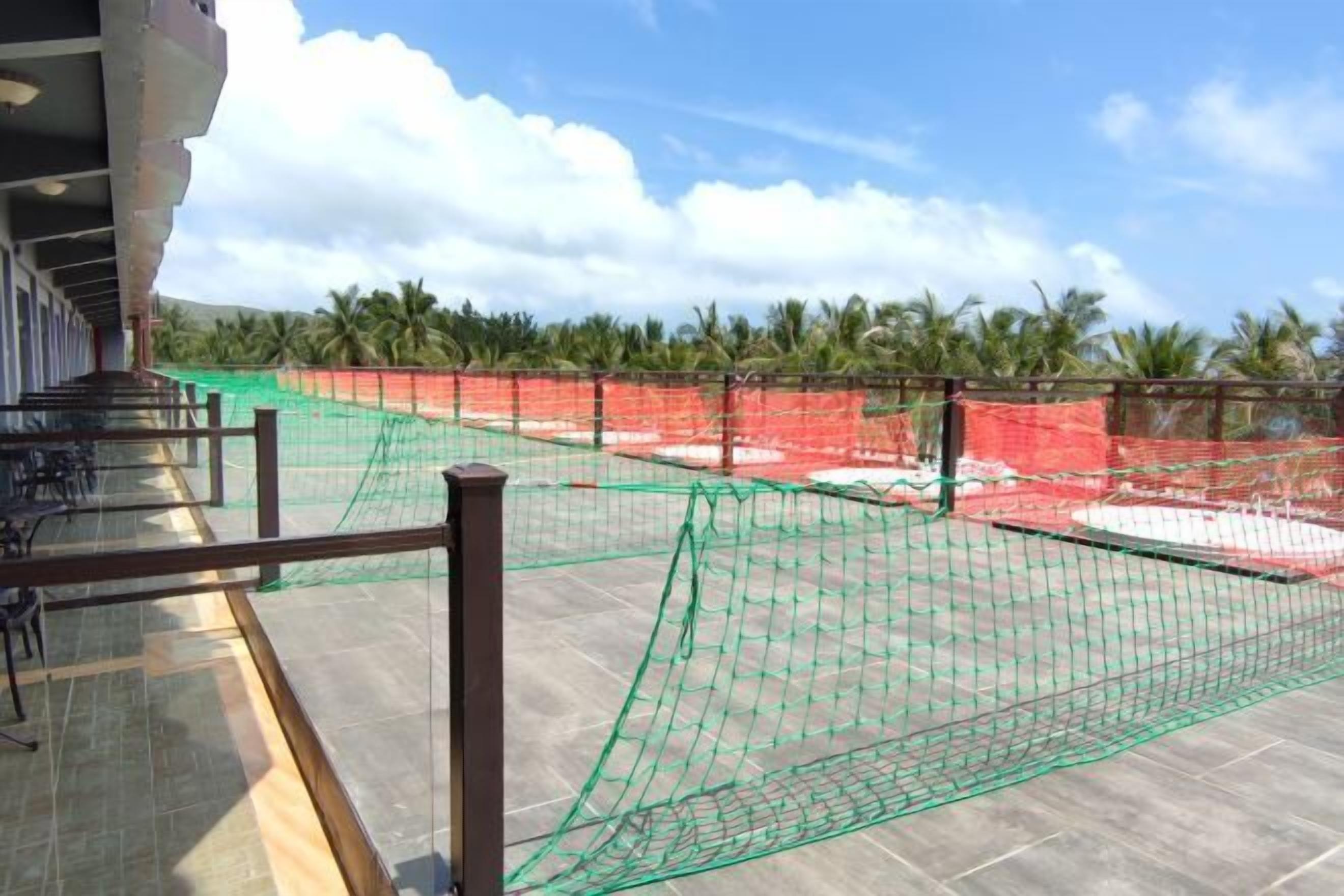 A hotel rooftop with netted areas and palm trees in the background.