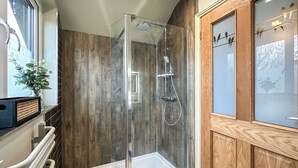 Une salle de bain moderne avec une douche à parois de verre, un lambris en bois, une baignoire blanche et un miroir décoratif orné de silhouettes d’oiseaux.