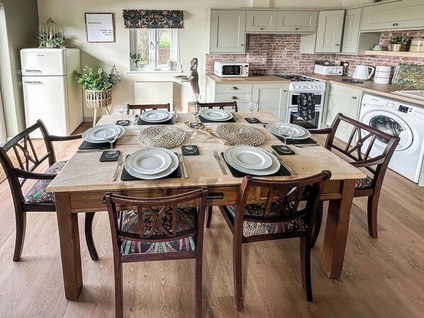 A dining area with a table set for six, surrounded by wooden chairs with patterned cushions.