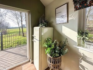 A room with a large window, a vintage refrigerator, and a wall-mounted sign.