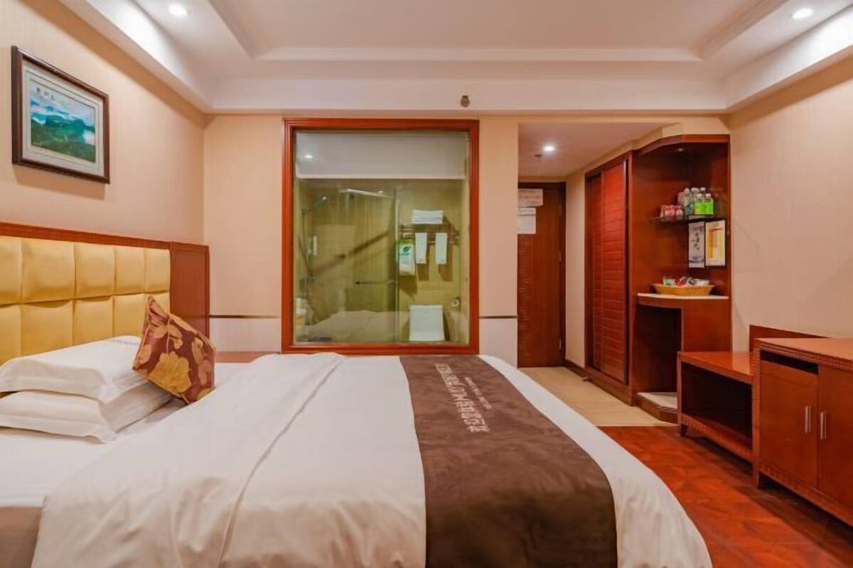 Habitación de hotel con una cama, puerta corredera al baño, armario de madera y un cuadro enmarcado en la pared.