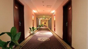 A hotel hallway with a patterned carpet, wooden doors, and potted plants. - Fulante Le Hotel (Tianmen Mountain Fengwan Road) (Zhangjiajie)