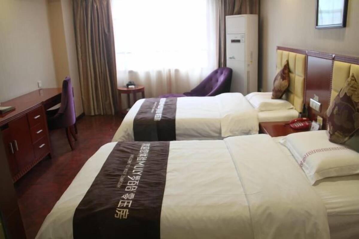 Habitación de hotel con dos camas, un escritorio, una silla, un armario y una mesita.