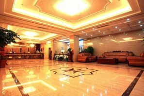 Um saguão de hotel com design de piso em formato de estrela, balcão de recepção e áreas de estar.