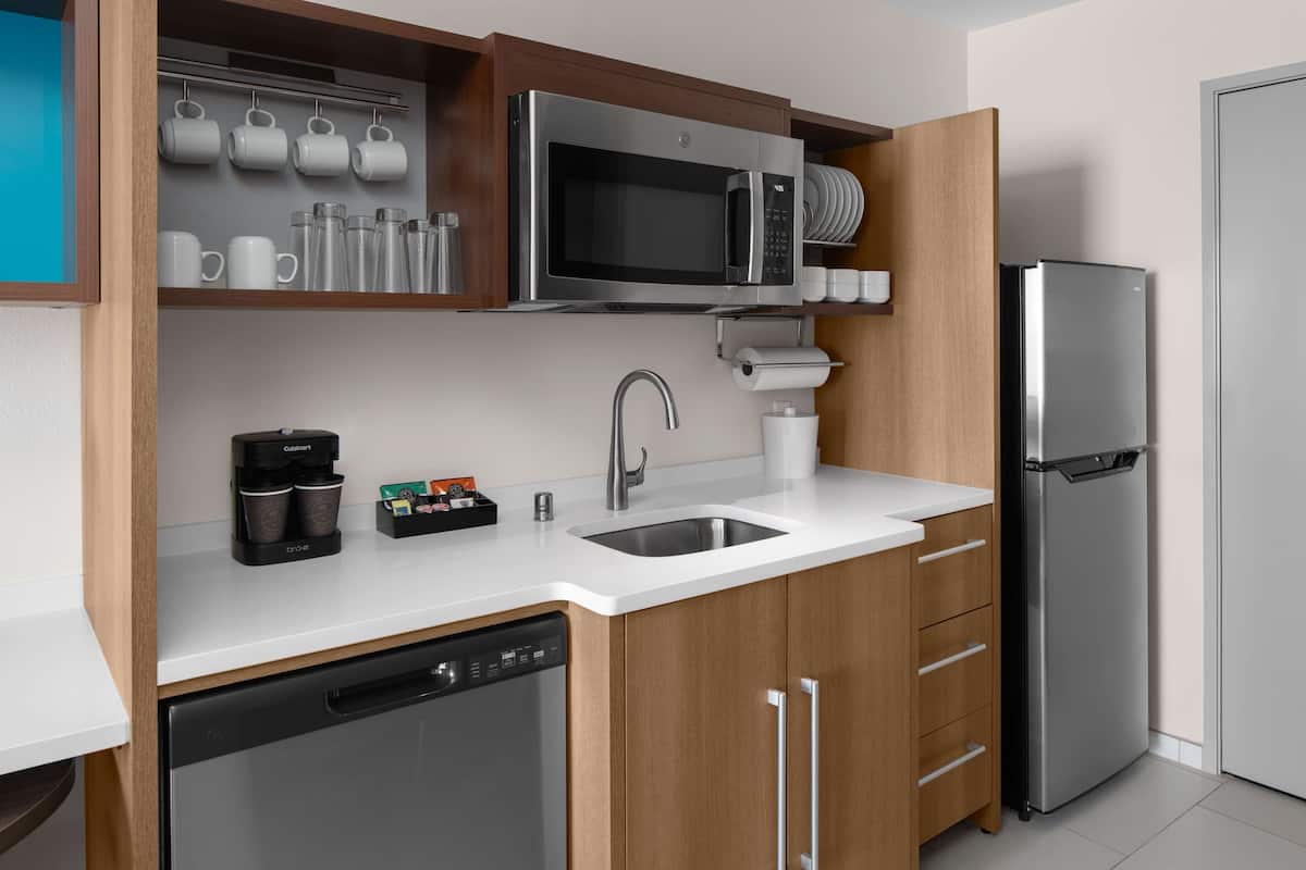 A modern kitchen with a built-in dishwasher, stainless steel refrigerator, and a microwave above the sink.