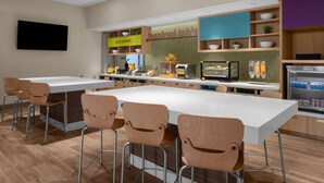 Un área de cocina moderna con una isla central, taburetes de bar y una barra desayunadora.