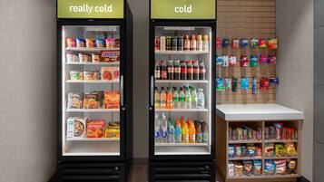 Dos dispensadores refrigerados para bebidas con etiquetas que indican 'muy frío' y 'frío', con varias bebidas y aperitivos en su interior.
