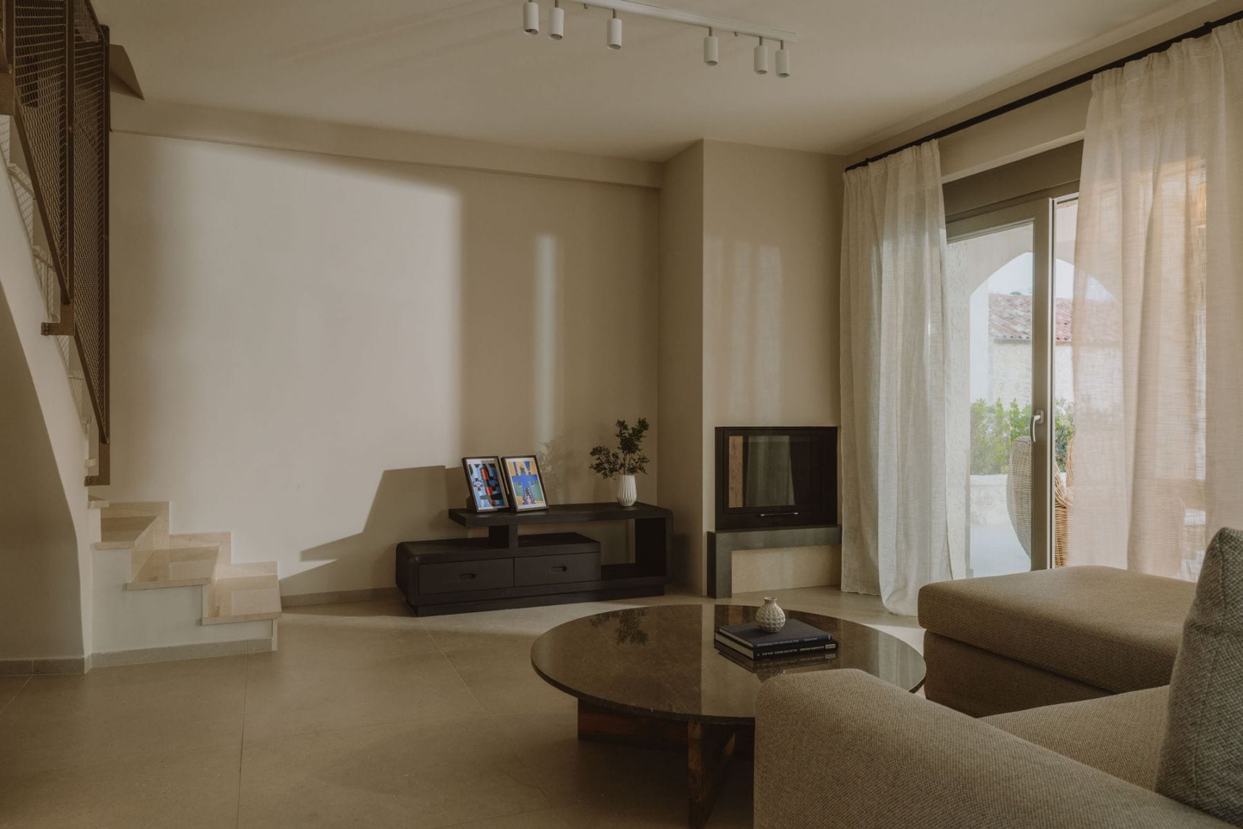 Ein modernes Wohnzimmer mit einer Couch, einem Couchtisch, einem Flachbildfernseher und einer Treppe.