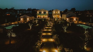 A large, illuminated estate with multiple buildings, a central pool, and a well-lit pathway. - Nama Seaside Villas (Preveza)