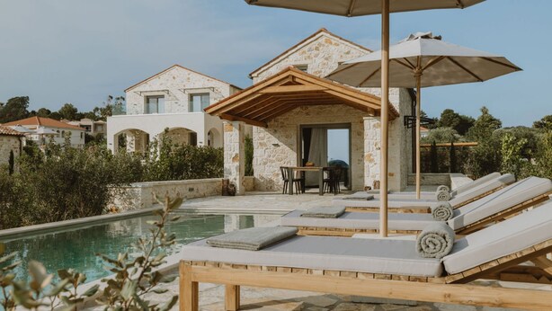 A poolside area with lounge chairs, a table, and an umbrella. - Nama Seaside Villas (Preveza)