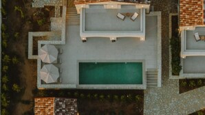 An aerial view of a resort with a swimming pool, outdoor seating, and a stone pathway. - Nama Seaside Villas (Preveza)