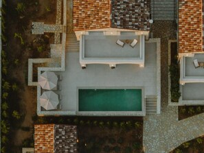 An aerial view of a resort with a swimming pool, outdoor seating, and a stone pathway. - Nama Seaside Villas (Preveza)