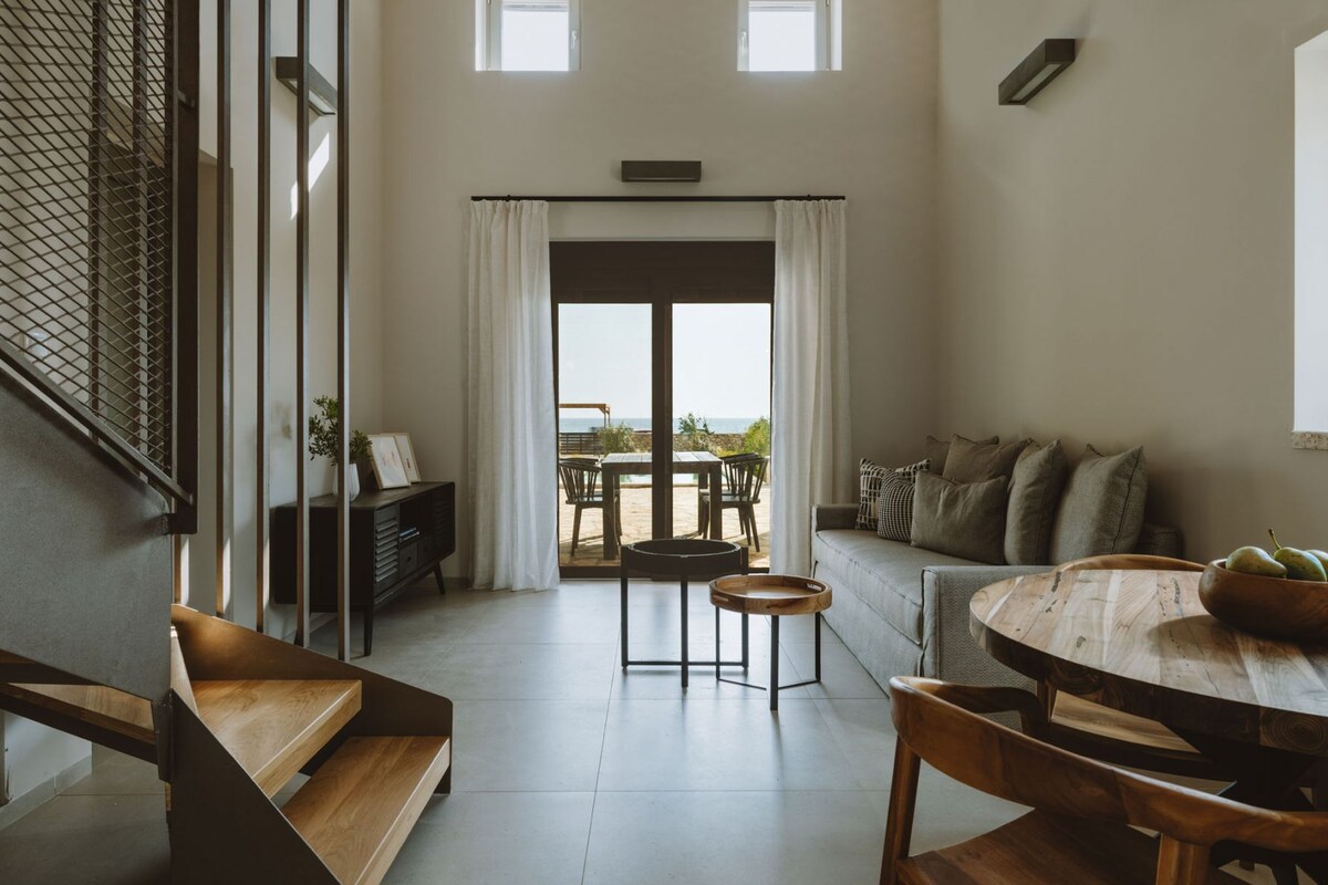 A spacious living area with a large window, a wooden table, and a sofa.
