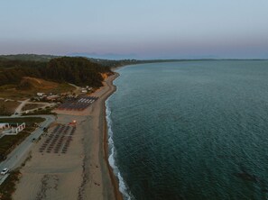 An aerial view of a beach with a parking lot and buildings in the background. - Nama Seaside Villas (Preveza)