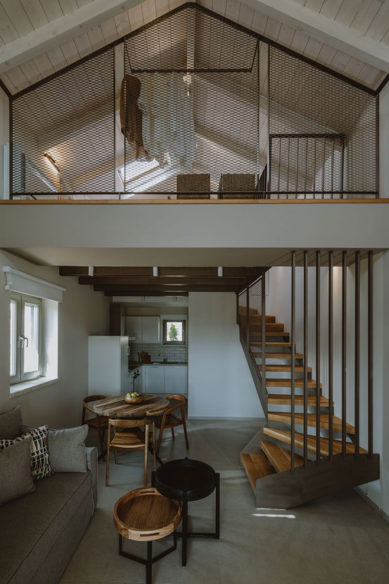 A loft-style interior with a mezzanine, open kitchen, and a staircase.