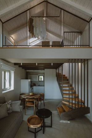A loft-style interior with a mezzanine, open kitchen, and a staircase. - Nama Seaside Villas (Preveza)