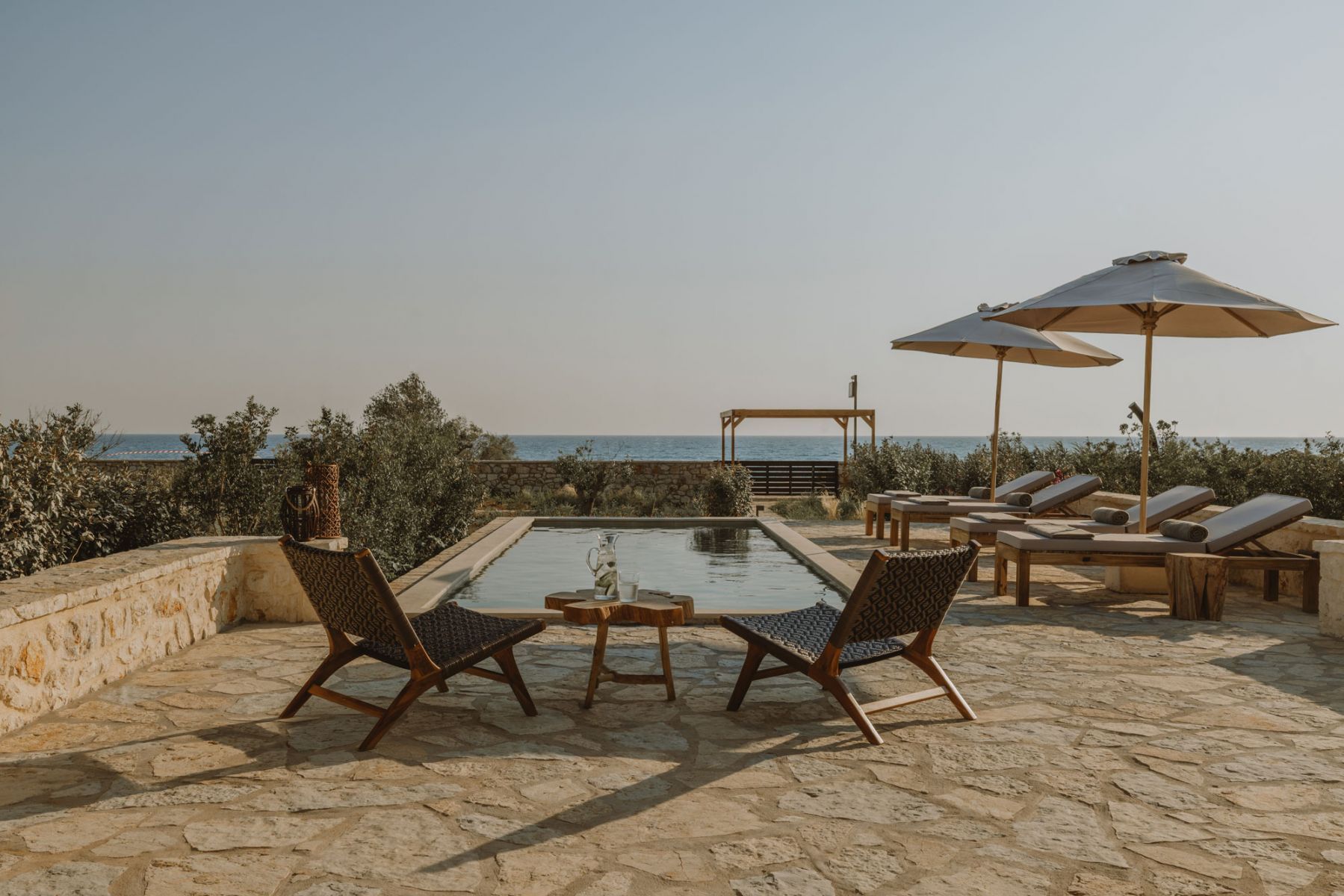 A pool area with lounge chairs and umbrellas, overlooking a body of water.