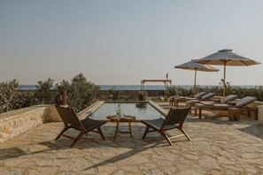 A pool area with lounge chairs and umbrellas, overlooking the sea. - Nama Seaside Villas (Preveza)
