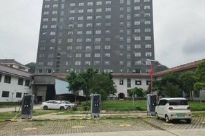 A multi-story building with a parking area in front. - Ningxin International Hotel (Luocheng)