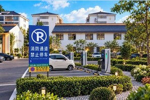 A hotel parking area with a no-parking sign, a car, and a building with multiple floors and a blue roof. - Ningxin International Hotel (Luocheng)