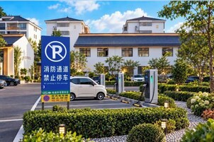 Un estacionamiento de hotel con un cartel de no estacionamiento, un coche y un edificio de varios pisos con techo azul.