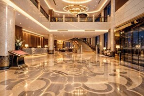 A spacious lobby with a grand staircase, marble flooring, and a reception desk. - Ningxin International Hotel (Luocheng)