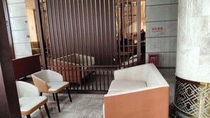 A modern interior with a sofa, chairs, a decorative pillar, and a patterned wall. - Ningxin International Hotel (Luocheng)
