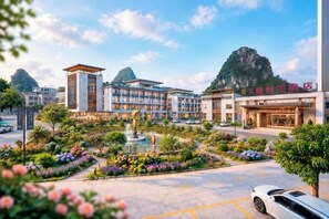 A hotel with a central courtyard, a fountain, and a mountain backdrop. - Ningxin International Hotel (Luocheng)