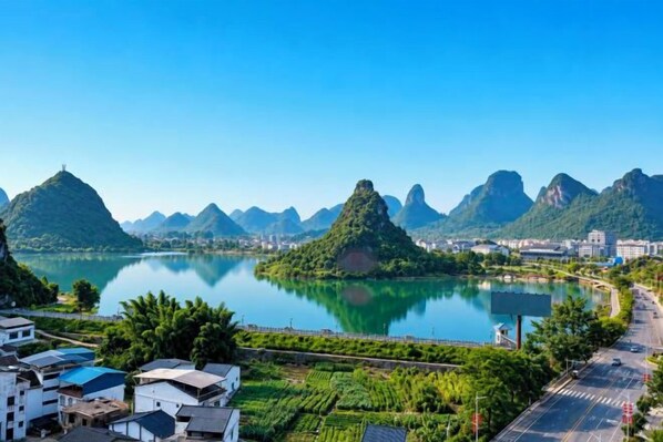 A river with mountains in the background, a bridge, and buildings along the riverbank. - Ningxin International Hotel (Luocheng)
