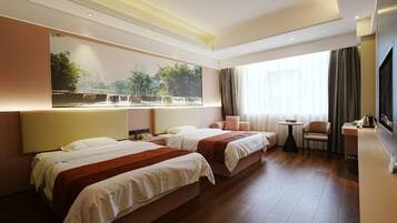 A hotel room with two beds, a large window with curtains, a small table, and a TV.