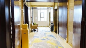 A hotel hallway with a patterned carpet, a reception desk, and a window at the end. - Ningxin International Hotel (Luocheng)