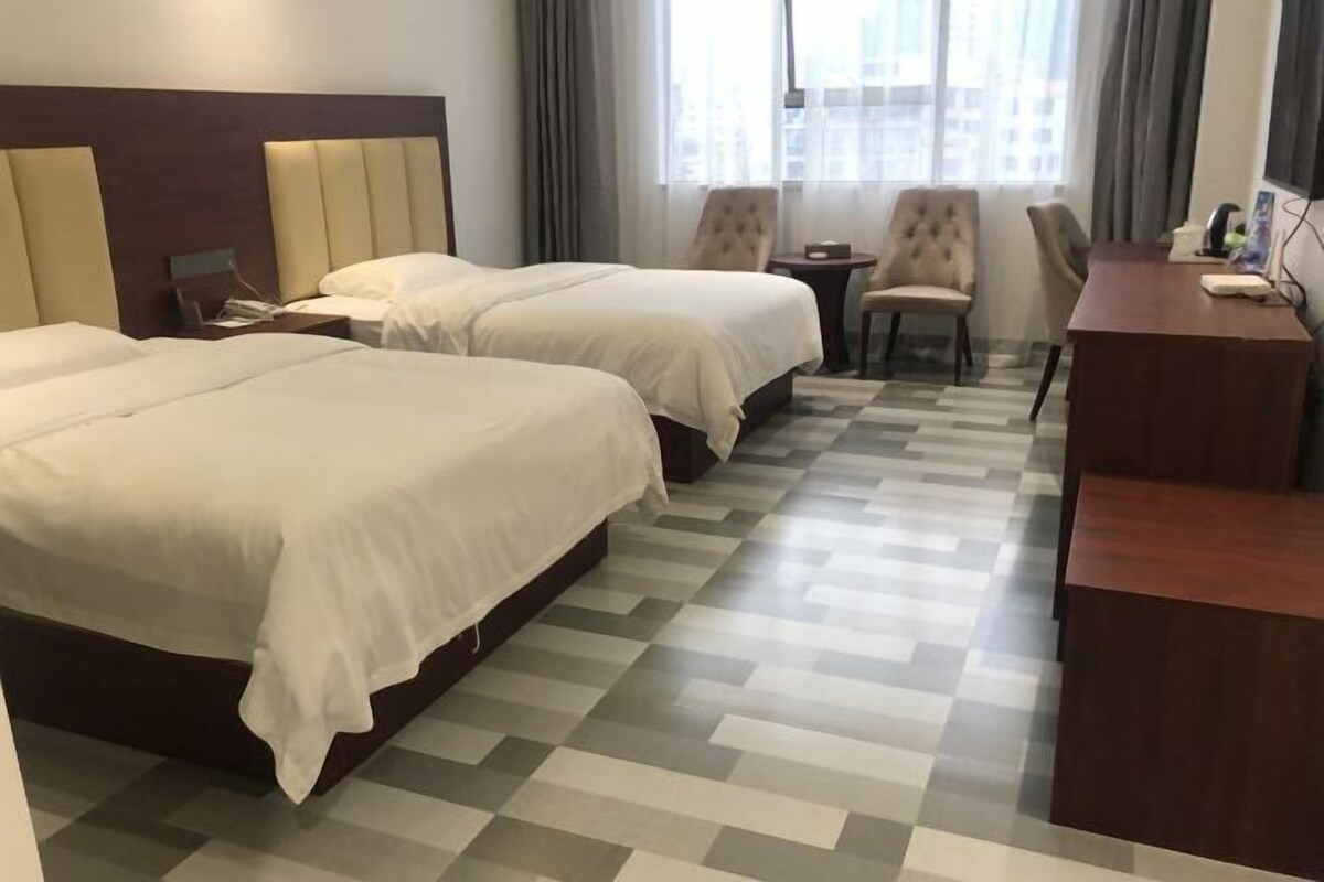 Habitación de hotel con dos camas, un escritorio y una silla.