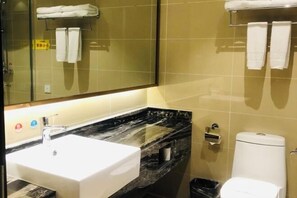 Un baño con lavamanos blanco, encimera de mármol negro, un espejo y un inodoro.