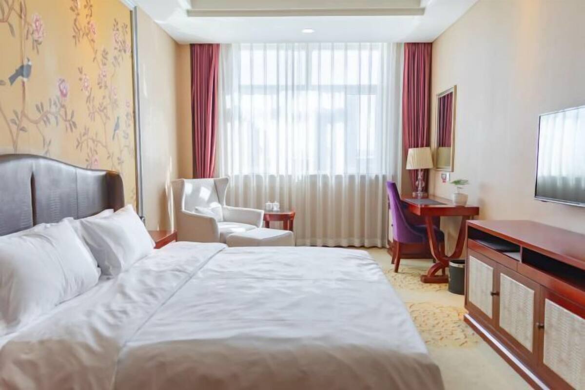 Una habitación de hotel con una cama grande, un escritorio, una silla y un televisor.