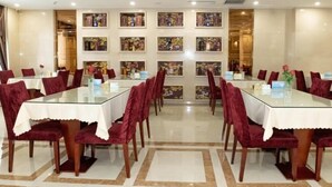 Un salón de conferencias con mesas de vidrio y sillas de terciopelo rojo, con una pared decorada con obras de arte enmarcada y un candelabro.