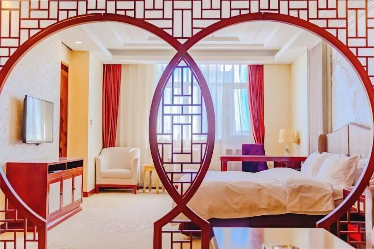 Una habitación de hotel con cama, televisor, escritorio y silla.