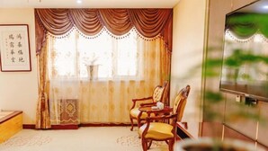 Una habitación con una silla tradicional, una mesita, un televisor y un adorno en la pared.