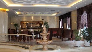 Un vestíbulo con una fuente central, una zona de bar y diversas disposiciones de asientos.