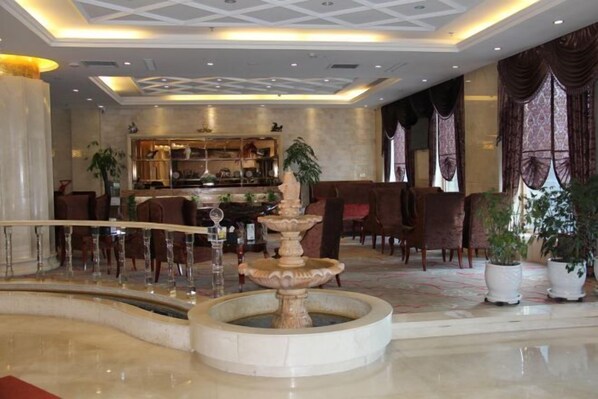 A lobby with a central fountain, a bar area, and seating arrangements.