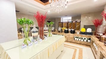 A reception area with a glass counter, decorative plants, and a chandelier.