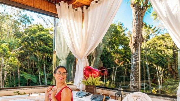 A room with a large window, a bed, and a view of a forest. - Chalé Caminho do Sol (Rancho Queimado)