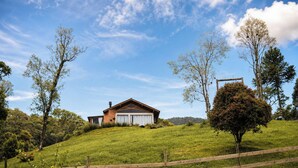 A house on a grassy hill with a clear sky. - Chalé Caminho do Sol (Rancho Queimado)