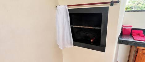 Un espacio pequeño y cerrado con una parrilla, un paño blanco y un recipiente rojo sobre una encimera.